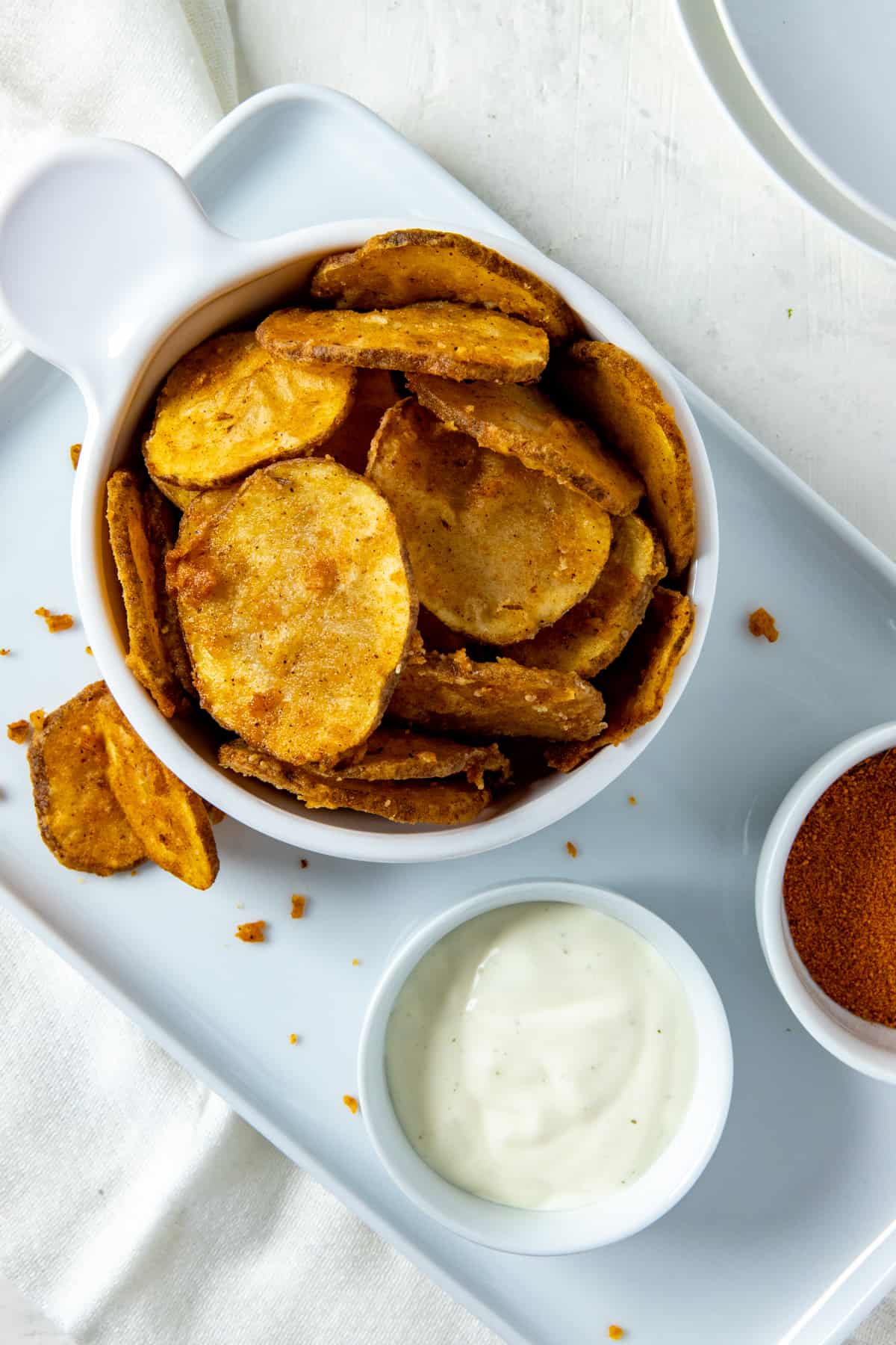 White bowl filled with fried potato slices plus a small bowl of ranch dressing on the side.