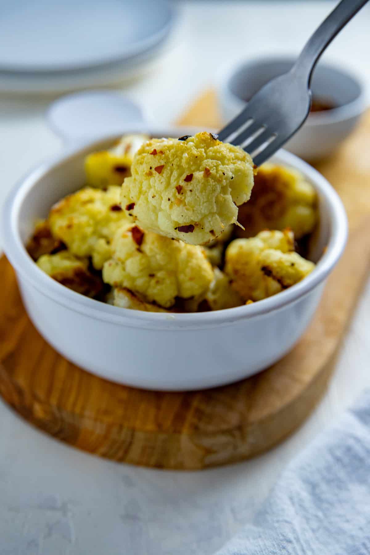 Bowl of parmesan roasted cauliflower with a fork holding a cauliflower floret.