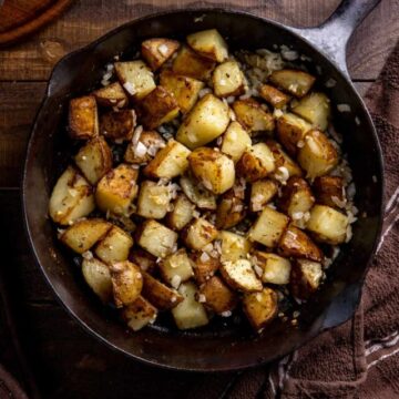 crispy fried potatoes with bits of onion in a cast iron skillet