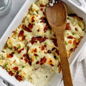 baked casserole in a white dish with wooden spoon on top
