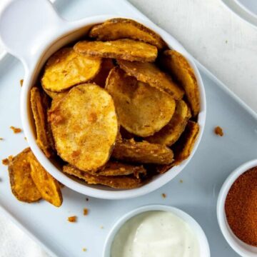 White bowl filled with fried potato slices plus a small bowl of ranch dressing on the side.