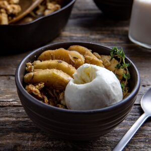 serving of apple crisp in blue bowl with vanilla ice cream on top