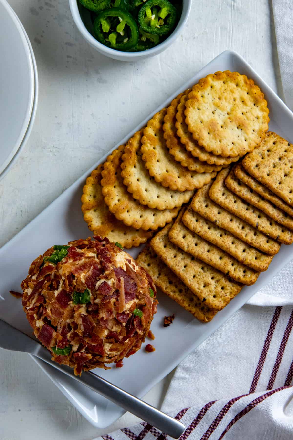Jalapeno Cheese ball and Crackers on white rectangular serving dish.