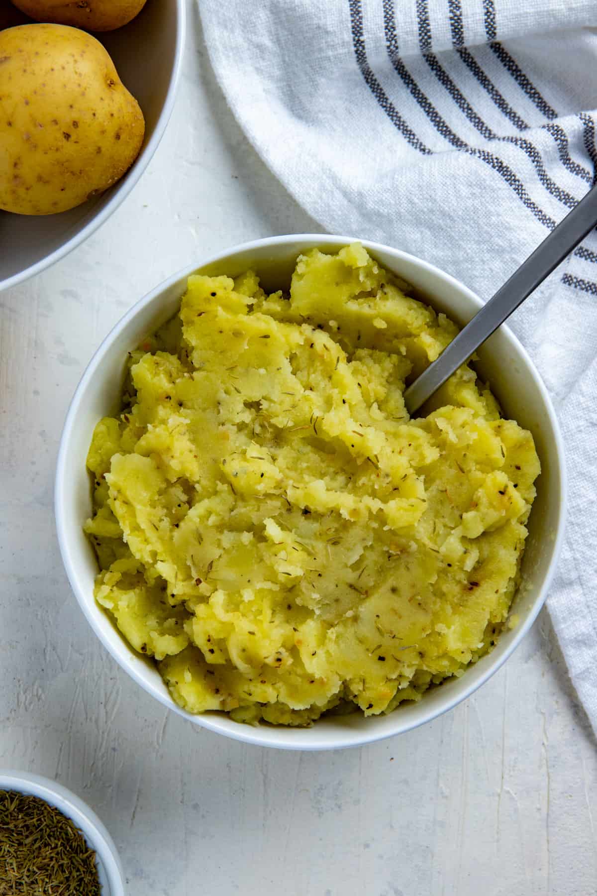 Mashed potatoes in white bowl with spoon inserted.