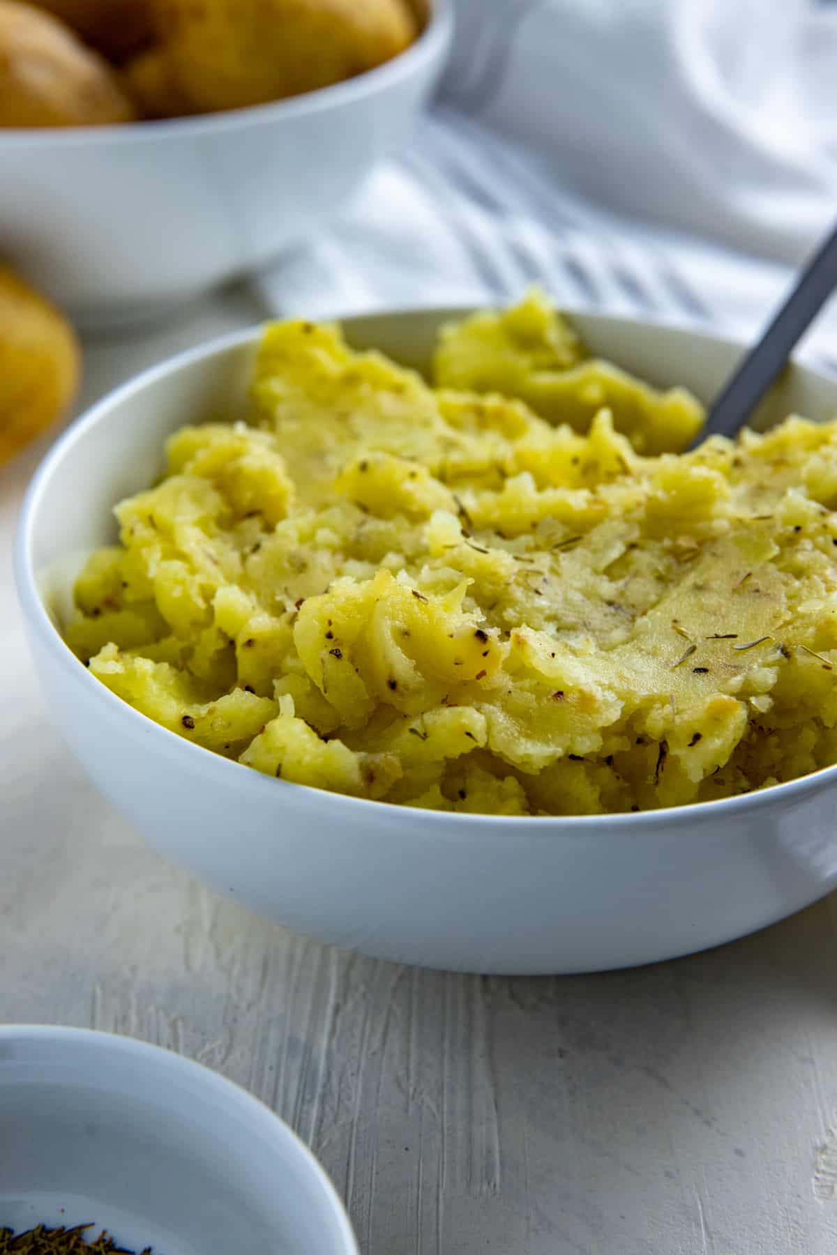 Mashed potatoes in white bowl with silver spoon inserted.