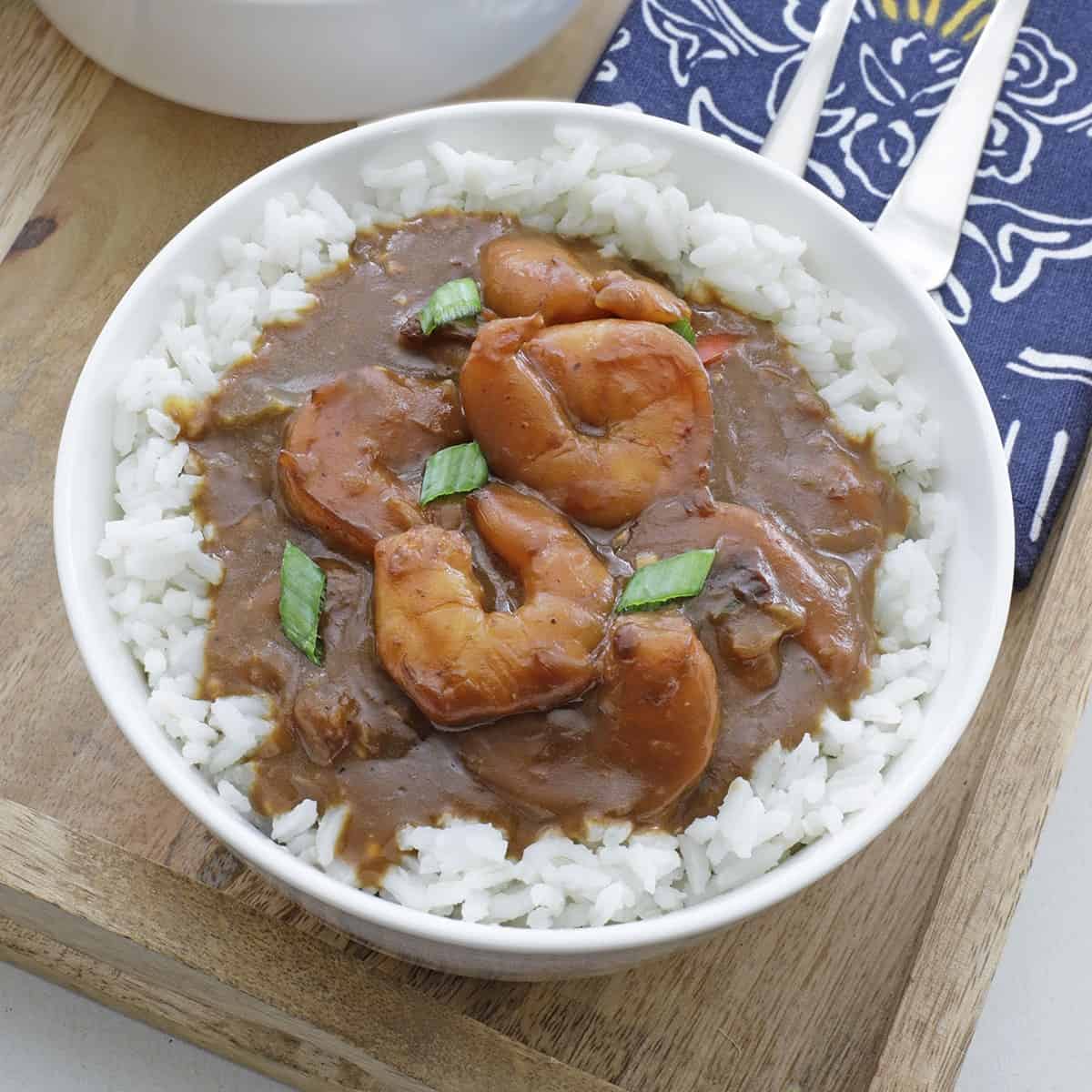 cooked shrimp stew over rice in white bowl.