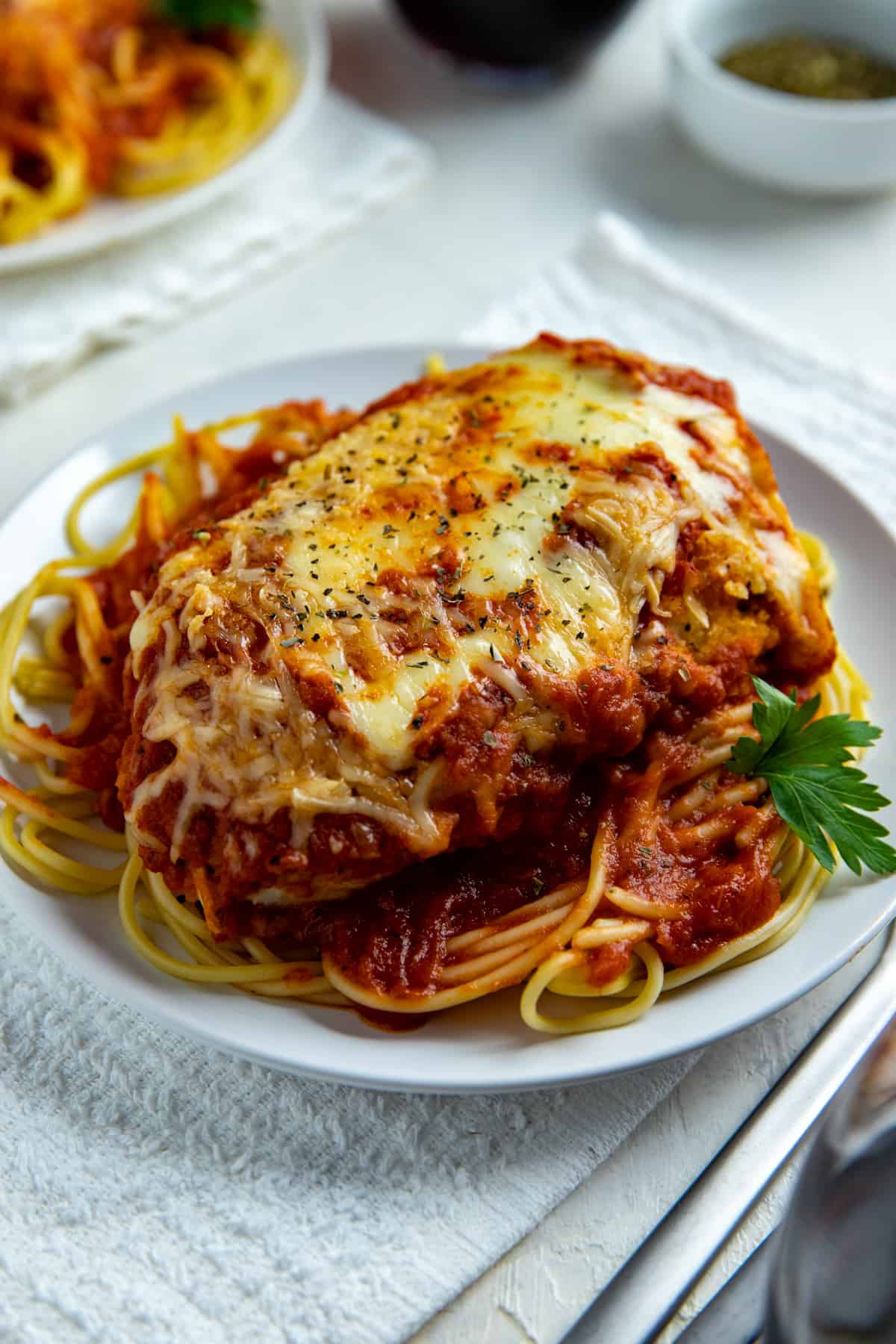 Chicken Parmesan over Spaghetti on white round plate.