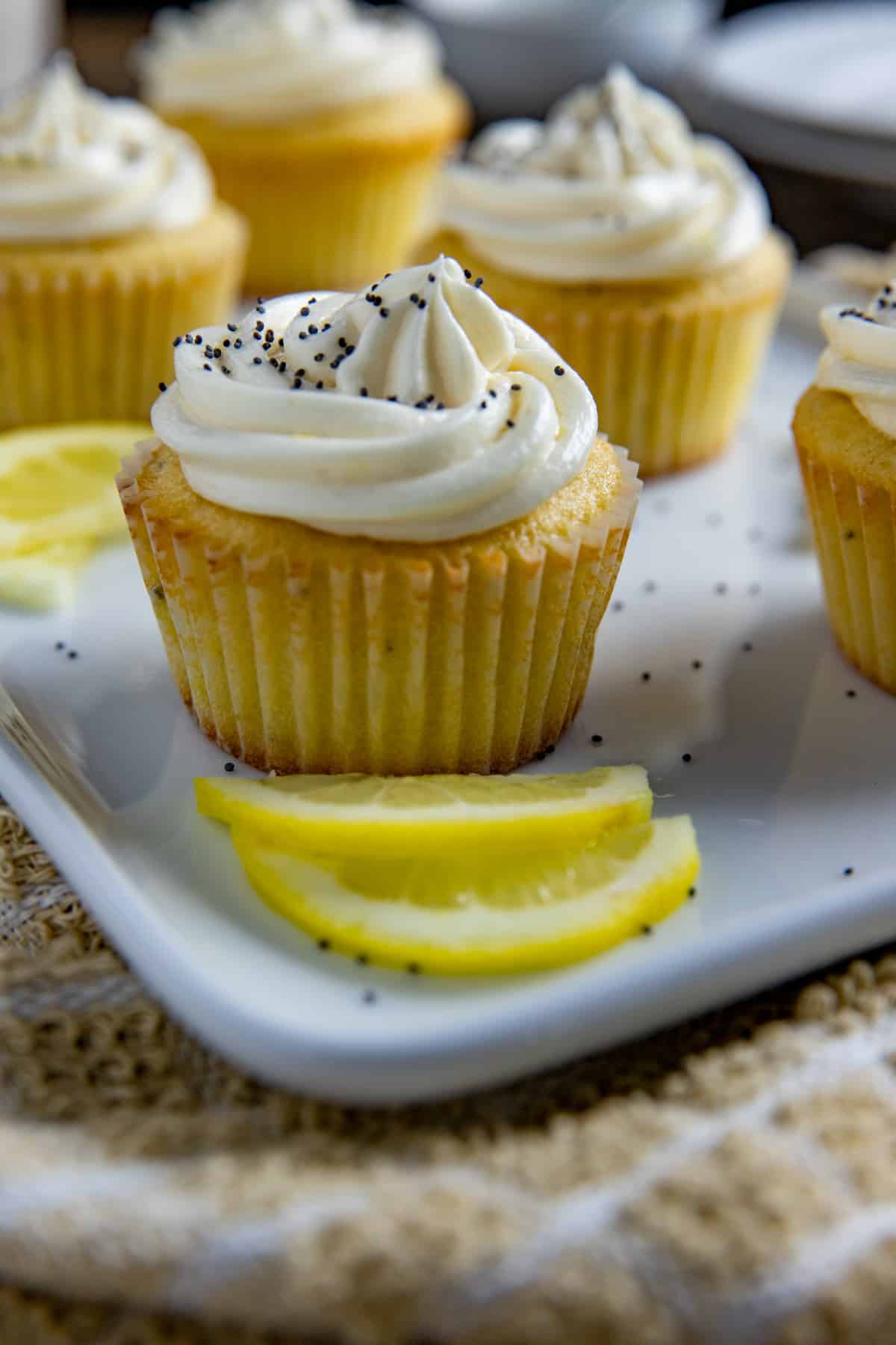 Frosted cupcakes on light blue serving platter with lemon slices as garnish.