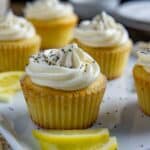 Frosted cupcakes on light blue serving platter with lemon slices as garnish.