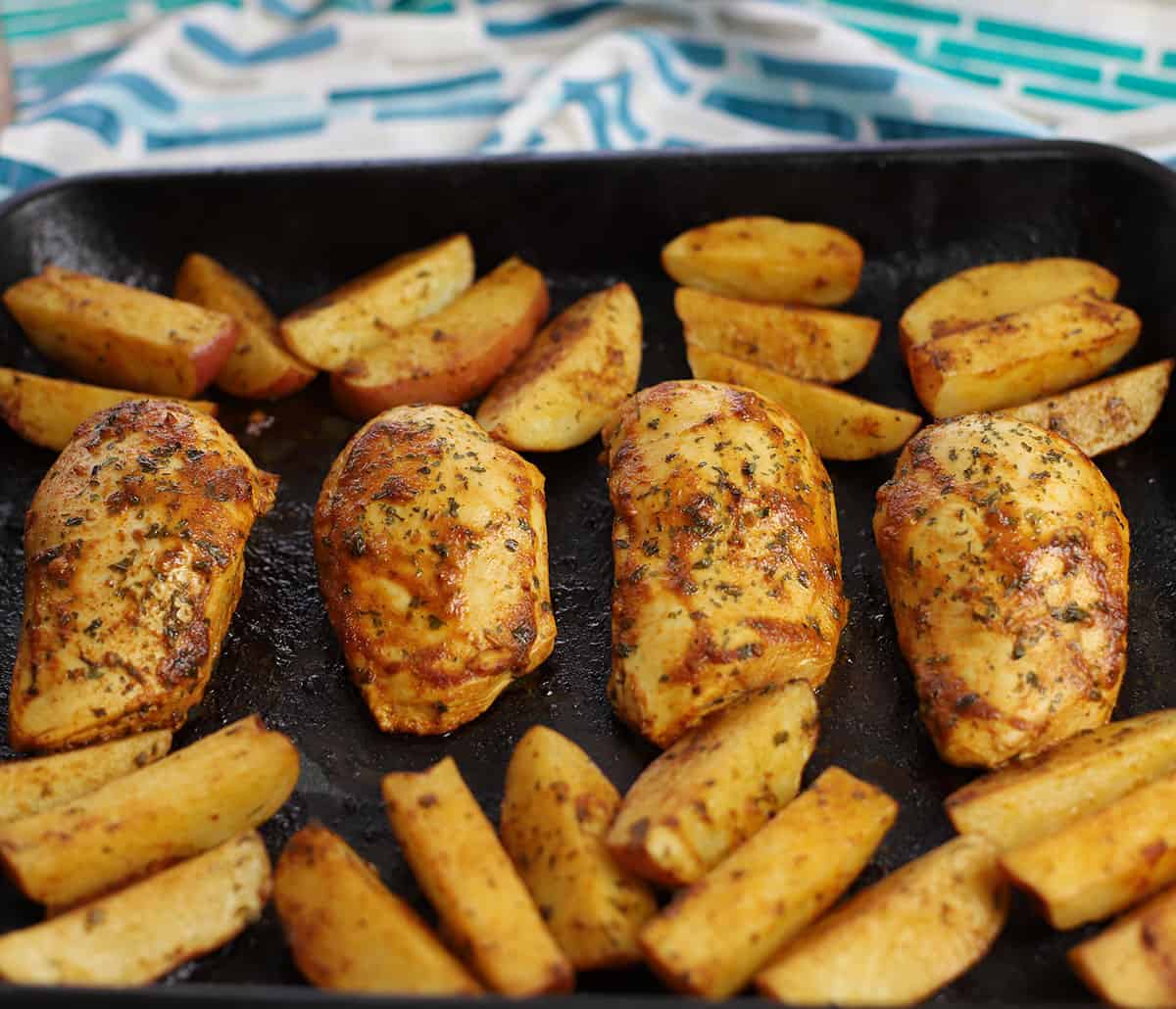 Baked chicken breasts and potatoes on sheet pan.