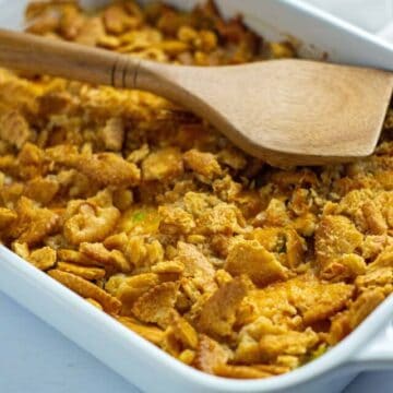 Baked cabbage casserole in white dish with a wooden spoon scooping out a serving.