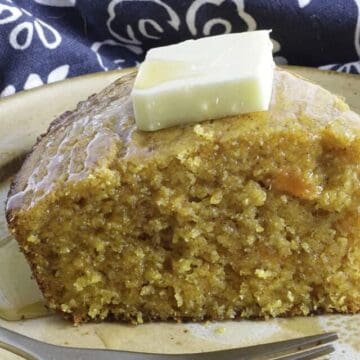 Slice of southern sweet potato cornbread on plate topping with butter and honey.
