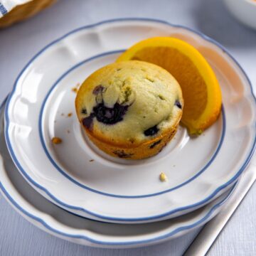 Baked muffin on white plate with a slice of fresh orange on the side.