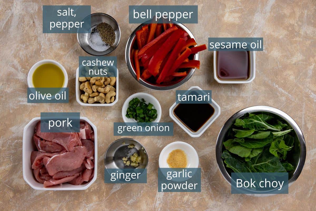 Ingredients measured out in individual containers.  Thinly sliced pork, sliced red pepper strips, Bok choy leaves, sliced green onions, cashews, olive oil, sesame oil, tamari, ginger, garlic powder, salt, and pepper.