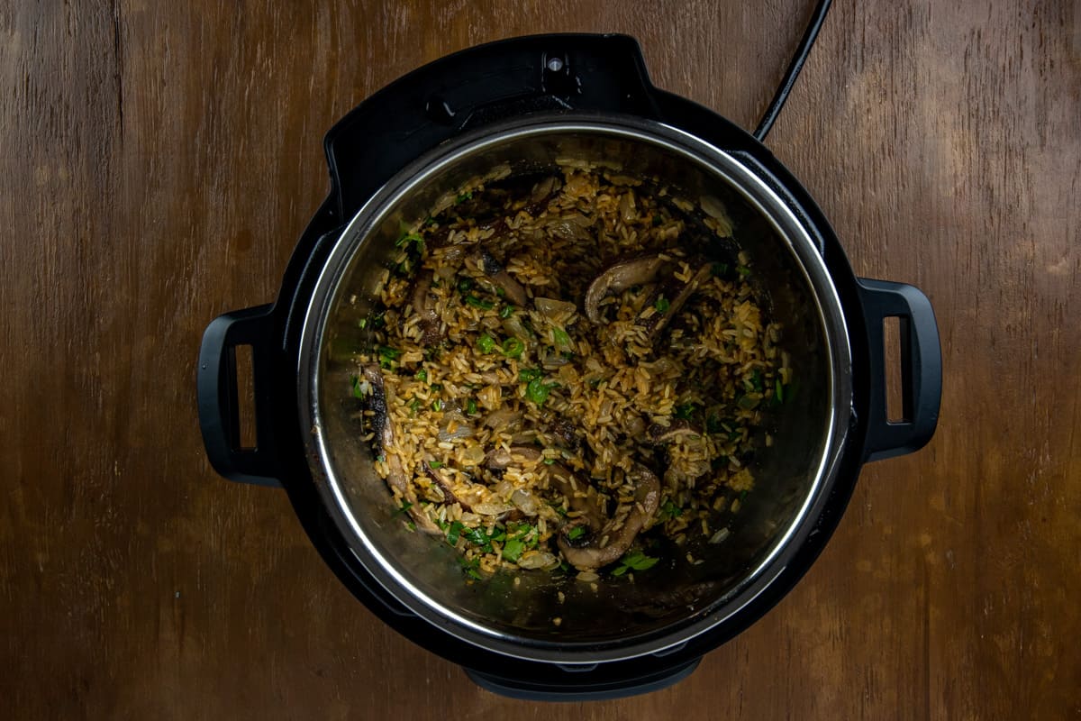 Cooked mushroom rice with sliced green onion on top in the Instant Pot.