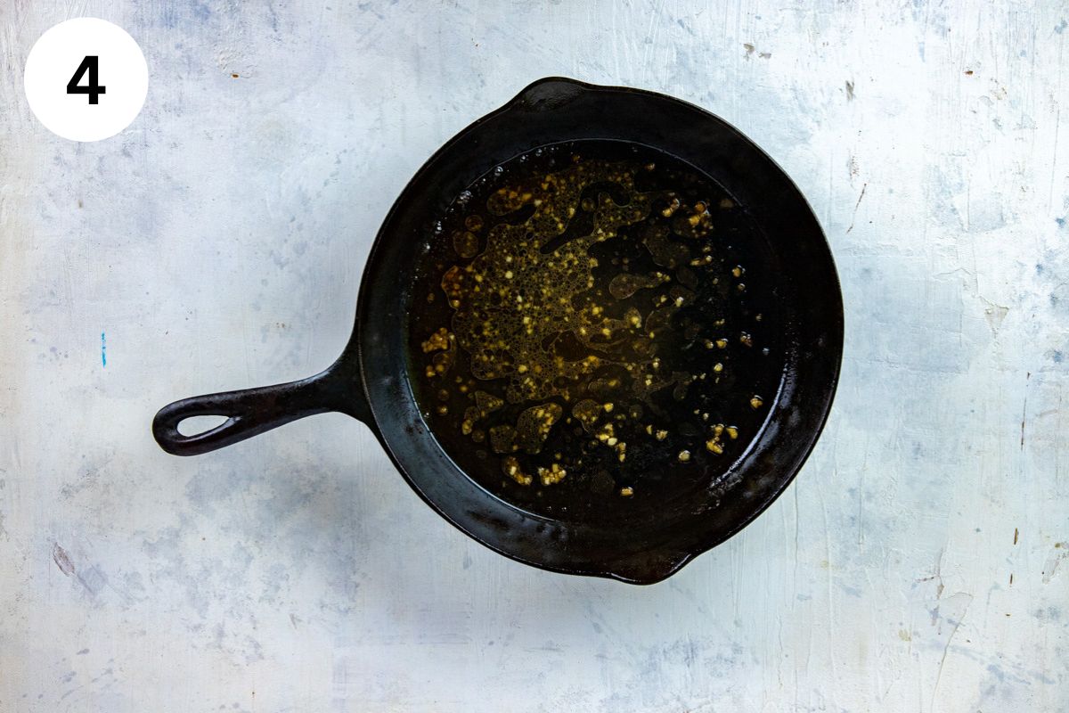 Lemon juice, broth, and minced garlic in a cast iron skillet.