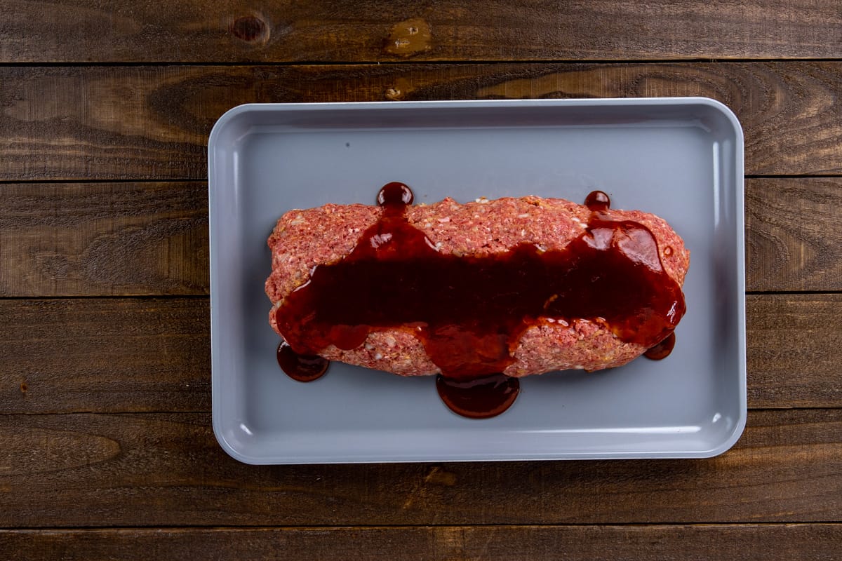 Unbaled meatloaf in a rimmed sheet pan with glaze on top.