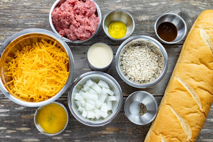 Ingredients measured out in individual containers with a whole loaf of French bread on the side.