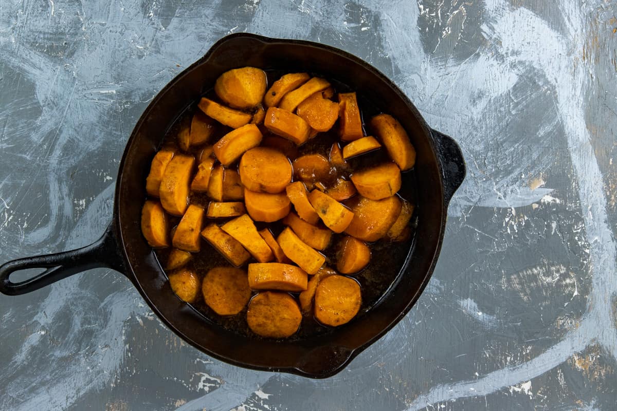 Uncooked sliced sweet potatoes, butter, and seasonings in skillet.