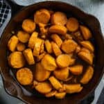 Cooked candied sweet potatoes in a cast iron skillet.