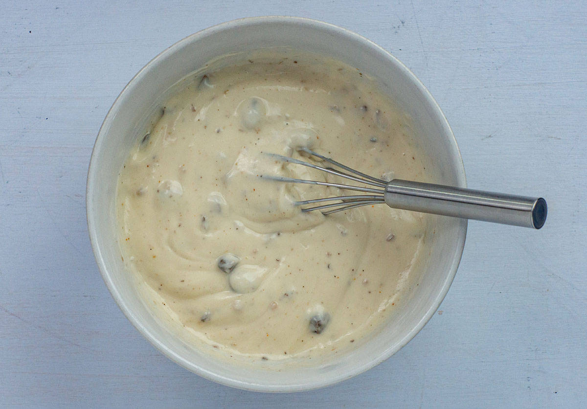Bowl of cream of mushroom soup and mayo mixed together with a whisk in the bowl.