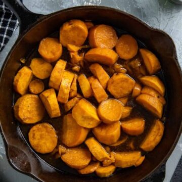 Cooked candied sweet potatoes in a cast iron skillet.