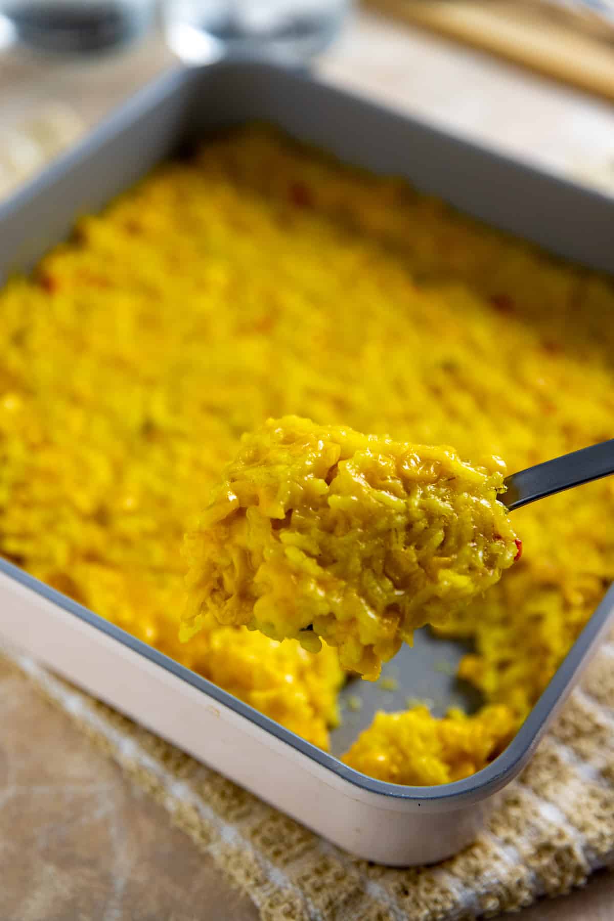 Square pan with cooked corn and rice casserole.  Spoon scooping out a serving.