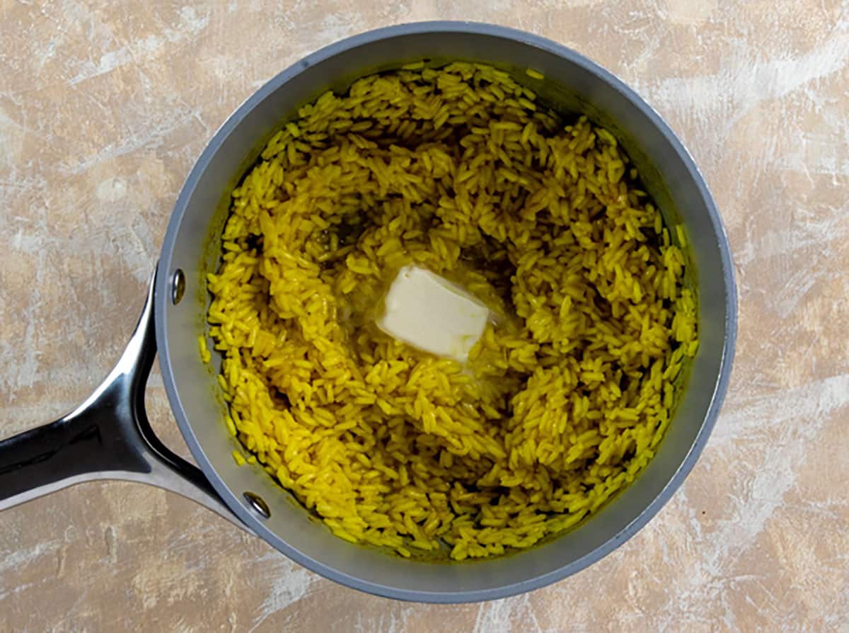 Cooked rice with pat of butter on top.
