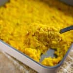 Square pan with cooked corn and rice casserole. Spoon scooping out a serving.