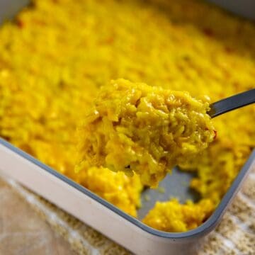 Square pan with cooked corn and rice casserole. Spoon scooping out a serving.