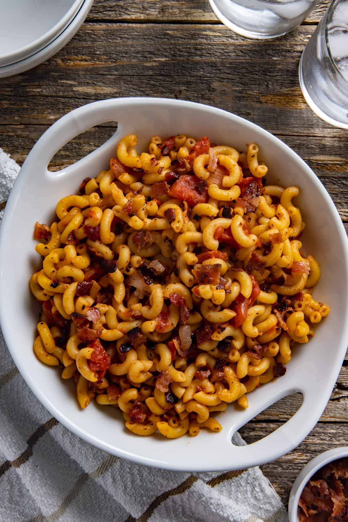 Cooked macaroni and tomatoes in white serving bowl.