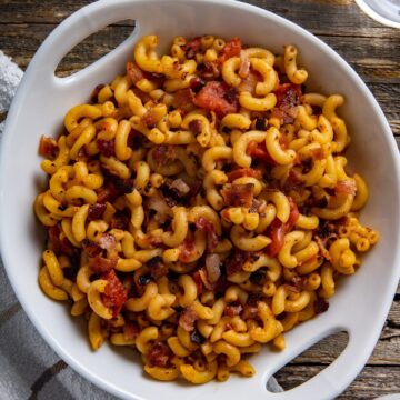 Cooked macaroni and tomatoes in white serving bowl.