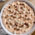 Mandarin Orange Salad topped with mini marshmallows and chopped pecans in white serving bowl.
