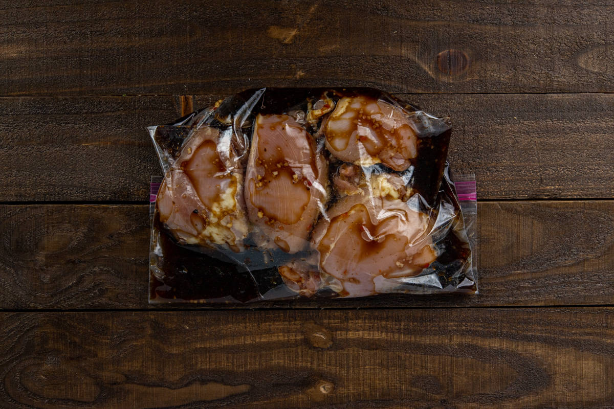 Chicken thighs and marinade in a plastic ziptop bag.