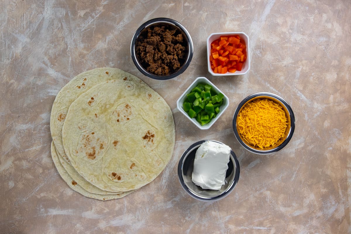 Ingredients measured out in individual containers with flour tortillas on the side.