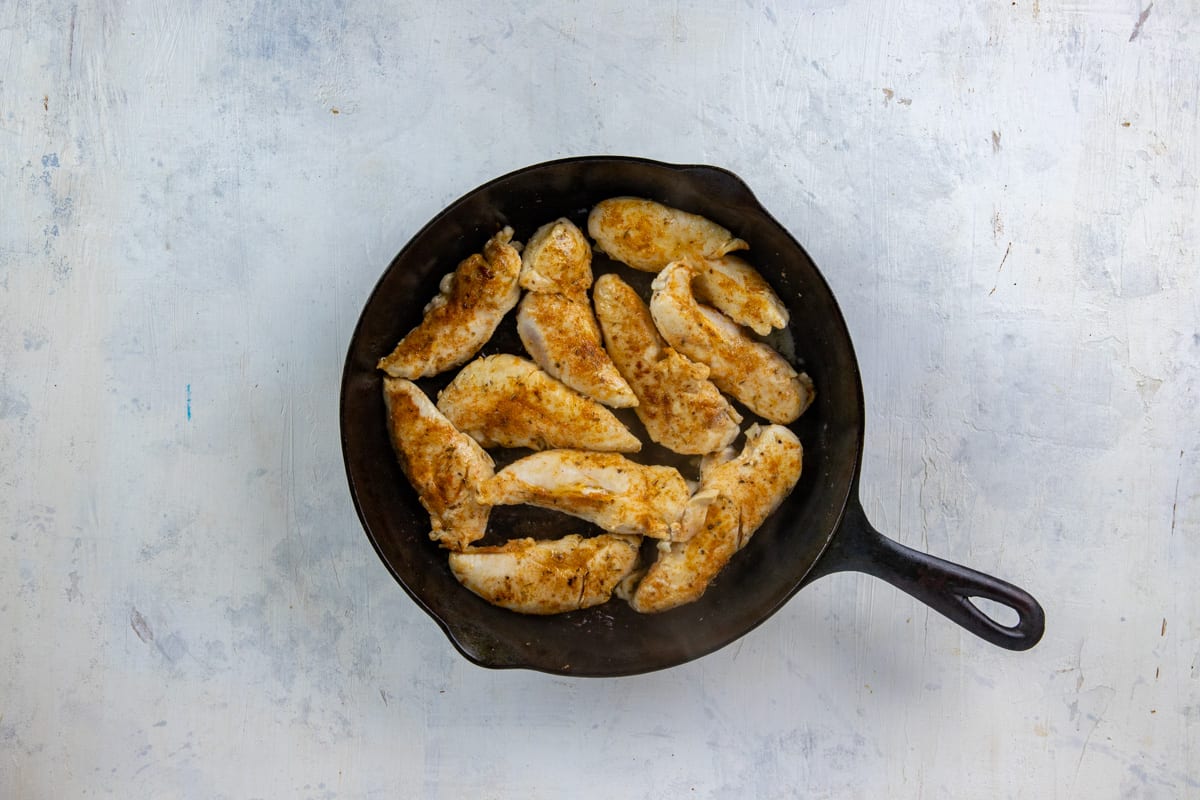 Seasoned and cooked chicken tenderloins in a cast iron skillet.