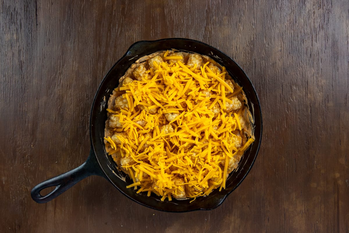 Shredded cheese on top of the frozen tater tots in the skillet.