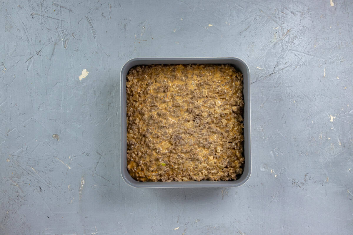 Ground beef mixture spread into a square baking pan.