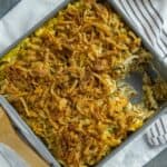 Baked casserole in square metal pan with one serving removed.