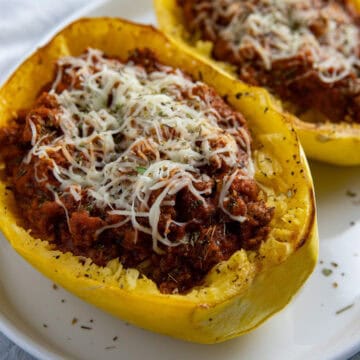 Two roasted spaghetti squash halves stuffed with meat sauce and topped with mozzarella cheese.