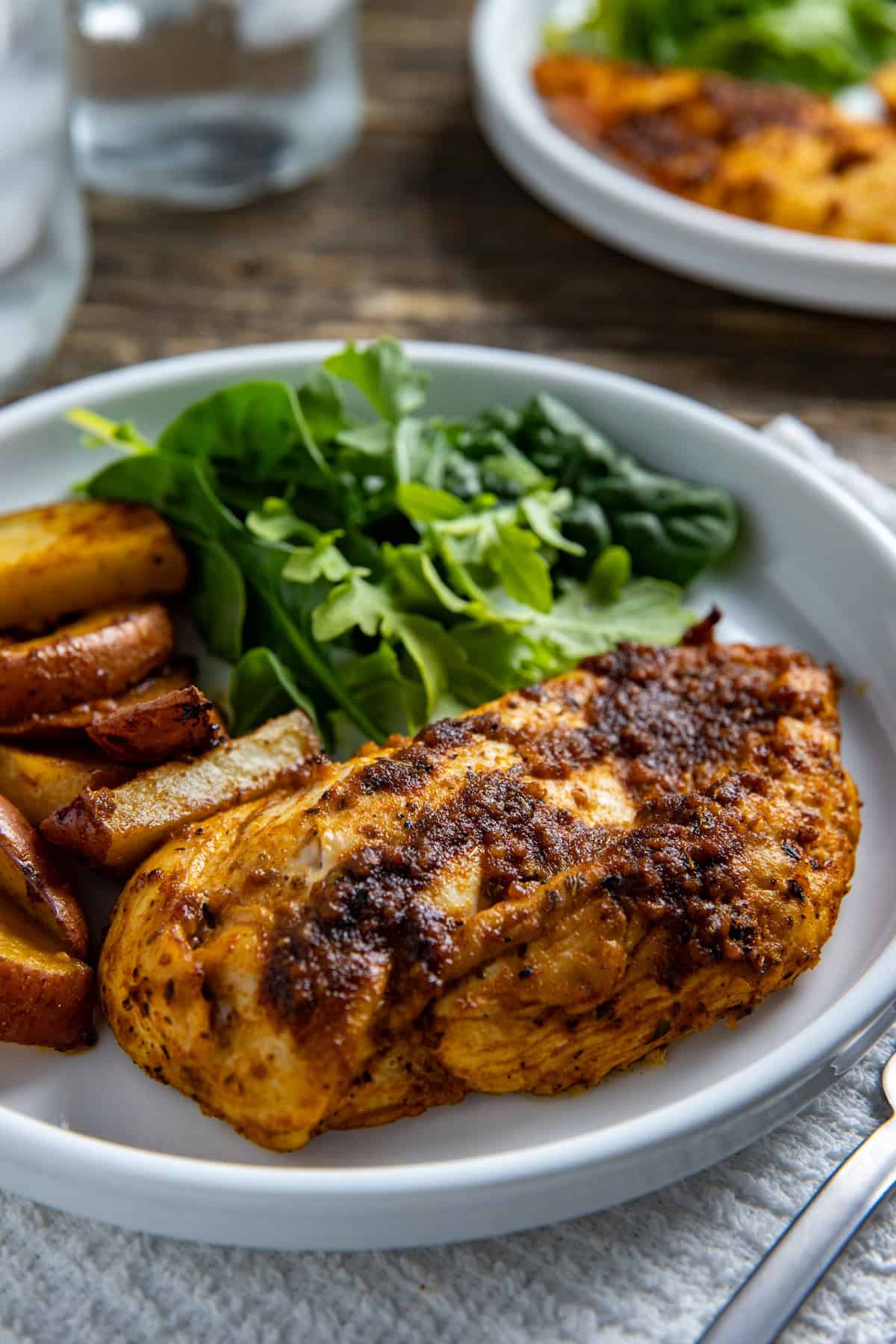 Baked chicken breast with potato wedges and green salad on the side.