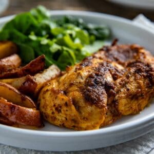 Baked chicken breast with potato wedges and green salad on the side.