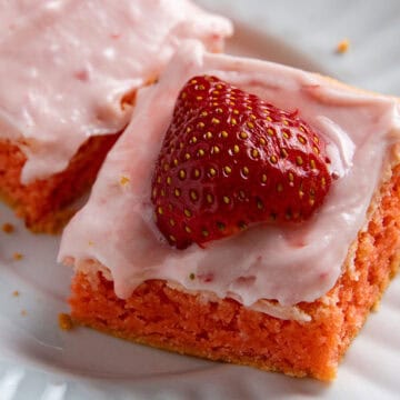 Frosted strawberry brownie topped with a fresh strawberry half.
