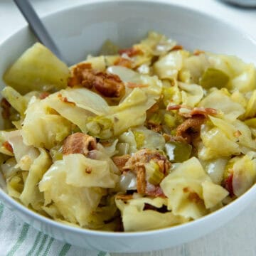 Cooked cabbage in white bowl.