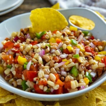 Dip mixed up in a large white serving bowl with corn chips on the side.