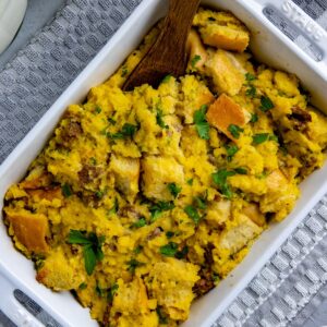 Baked cornbread sausage stuffing in white casserole dish.