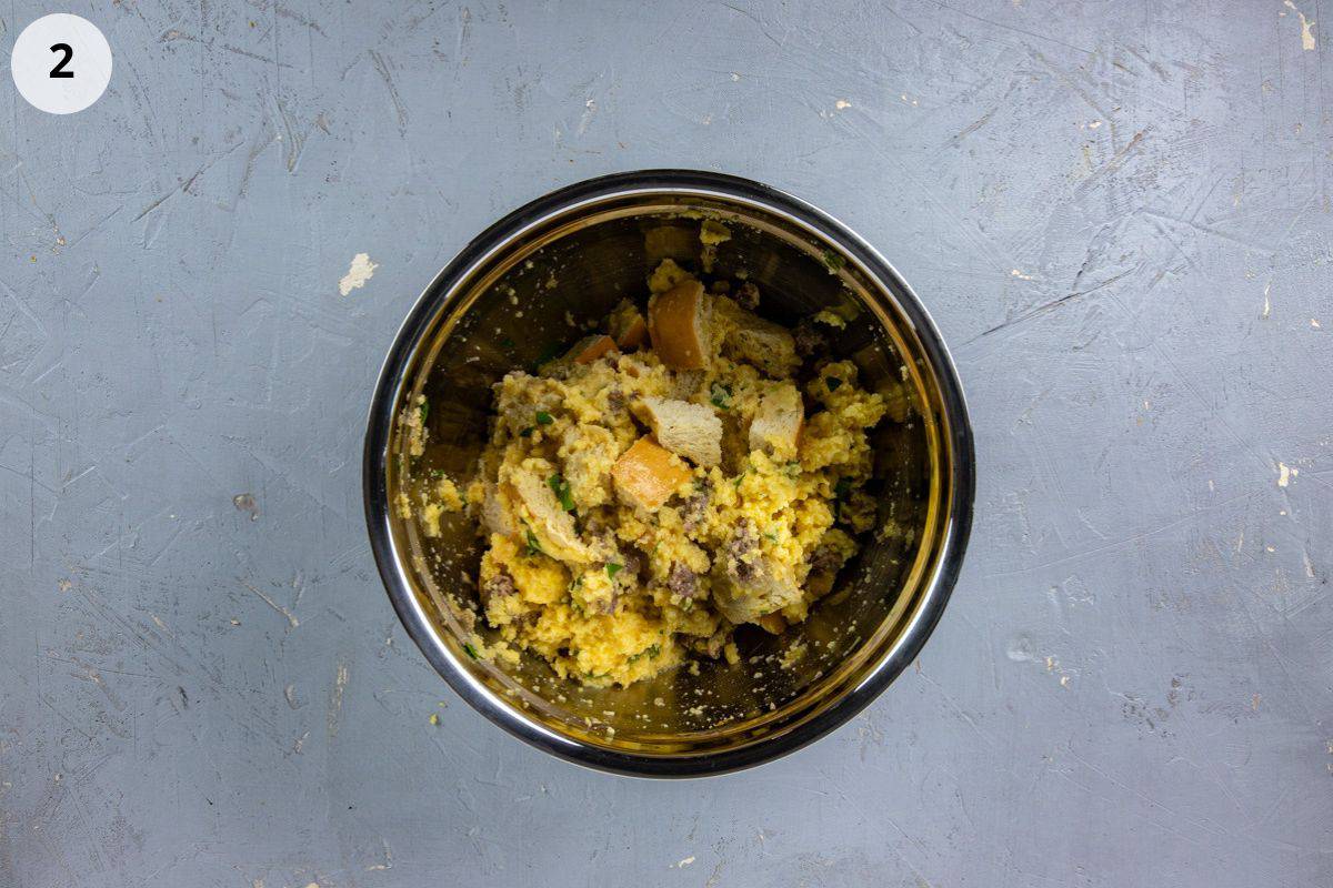 Sausage mixture, seasonings, cornbread cubes, French bread cubes, egg, and broth mix up in a bowl.