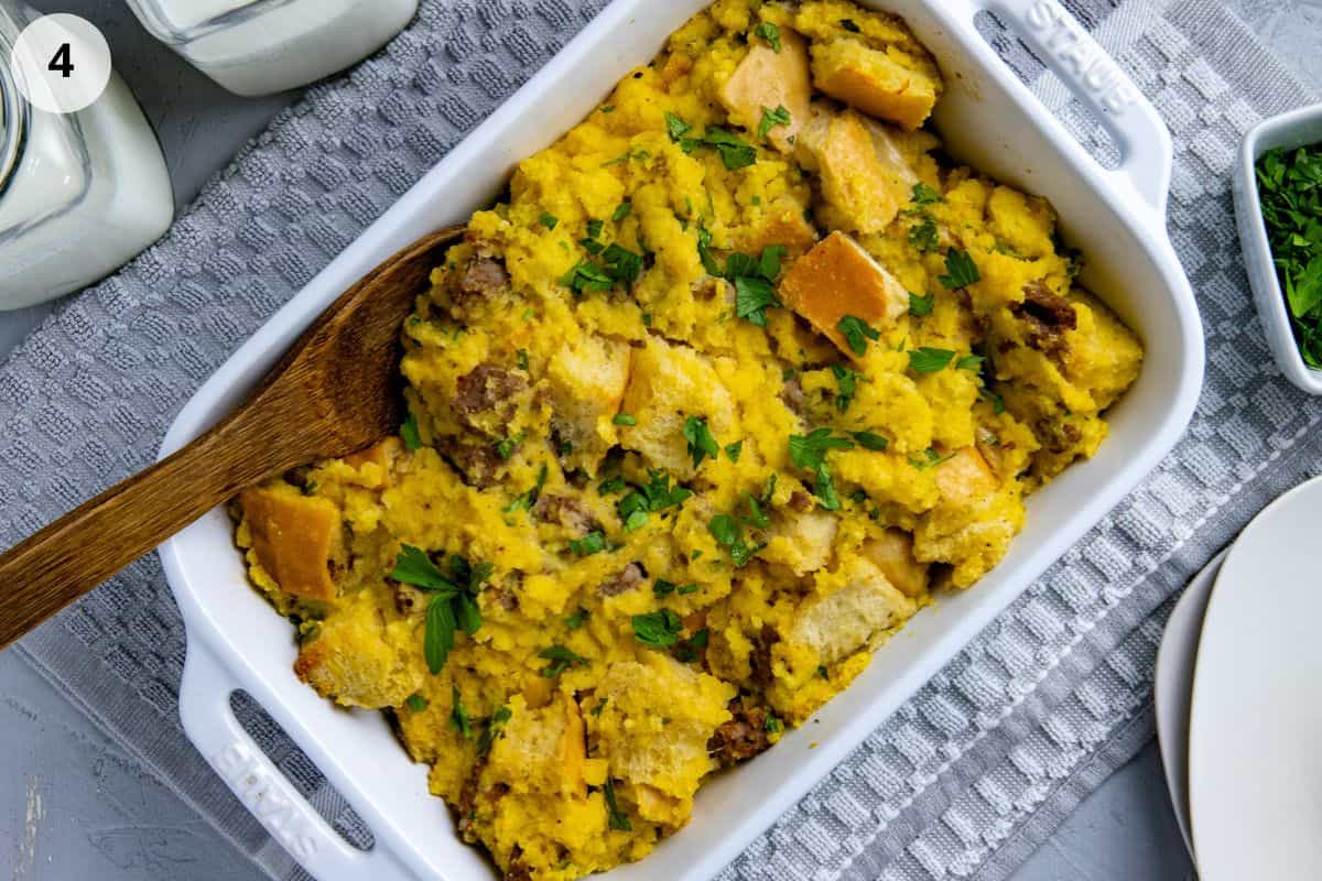 Baked dressing in white casserole dish with wooden spoon on the side.