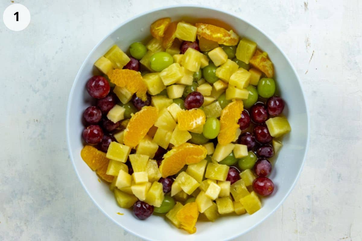 Diced apple, grapes, pineapple chunks, and orange segments in a bowl.