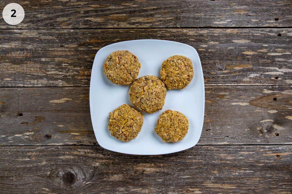 Five uncooked patties on a square white plate.